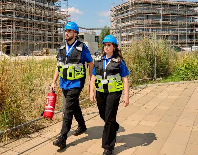 Sicherheitskräfte mit Feuerlöscher auf Baustelle unterwegs.