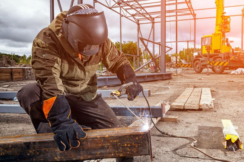 Schweißer arbeitet auf Baustelle mit Schutzkleidung.