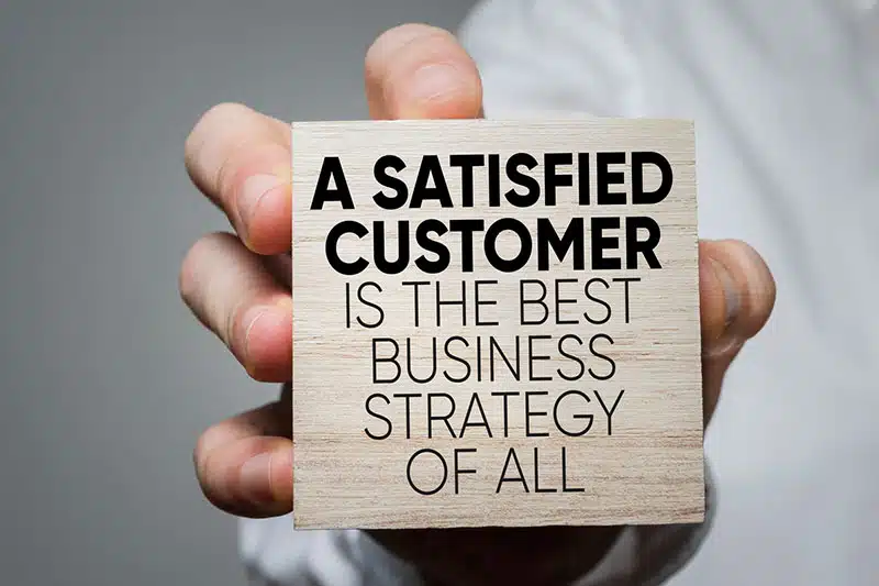 Hand hält Schild mit Kundenstrategie-Slogan