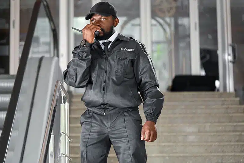 Sicherheitsbeamter spricht in Funkgerät vor Gebäude.