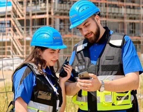 Bauarbeiter besprechen Projekt mit Tablet und Funkgerät.
