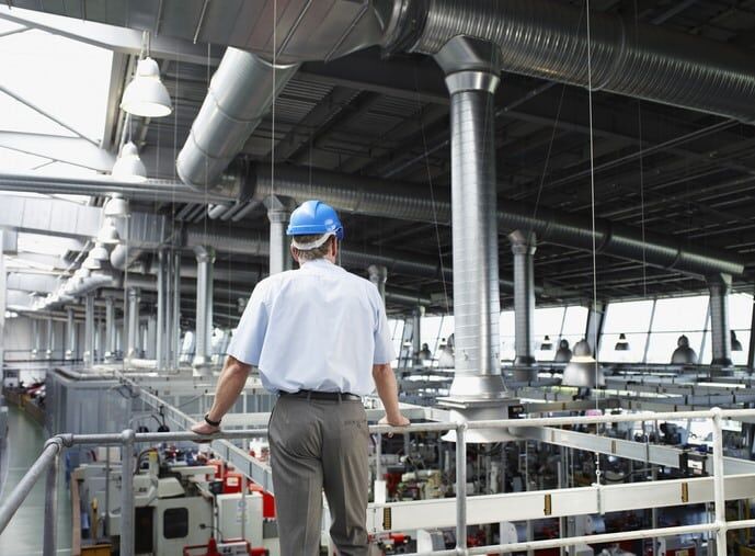 Ingenieur inspiziert industrielle Produktionshalle, seitlicher Blick