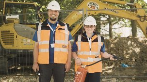 Bauarbeiter mit Schutzkleidung und Baugerät im Hintergrund